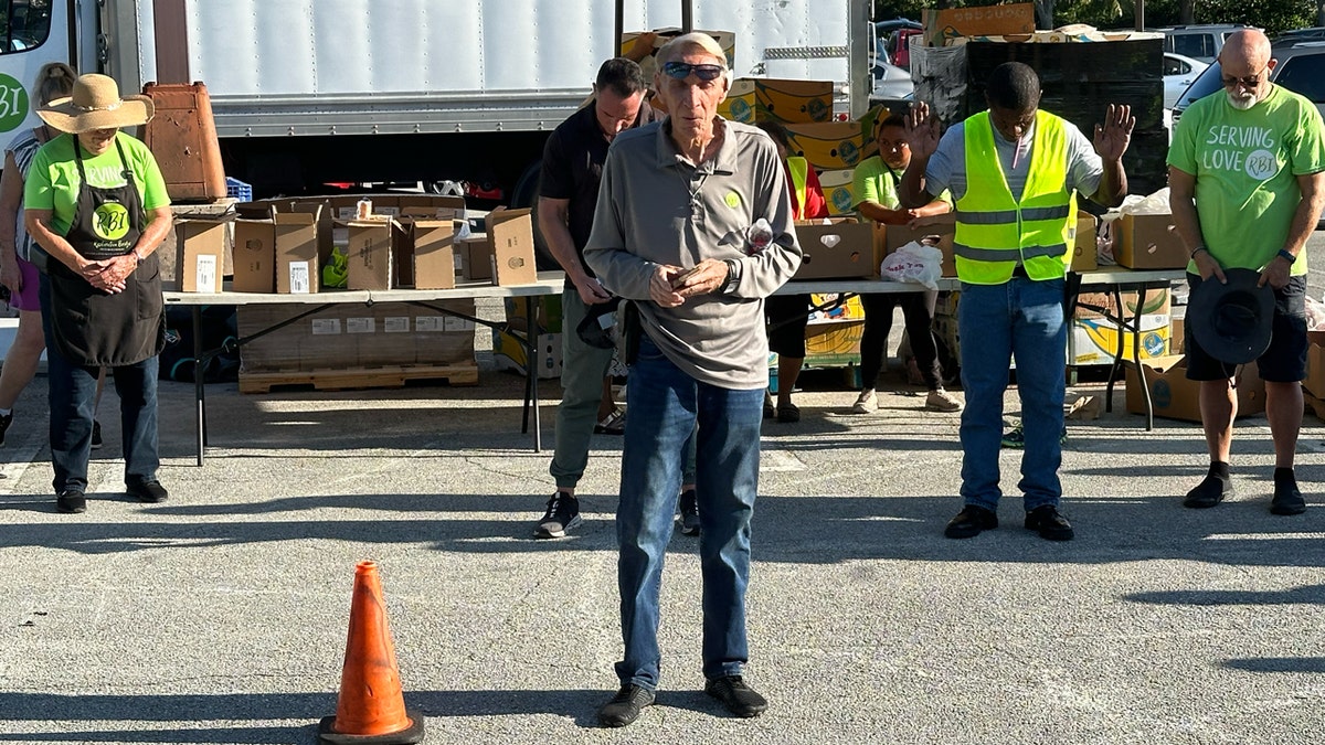 A pastor leads volunteers in prayer before Place of Hope's drive-thru food distribution line opens.