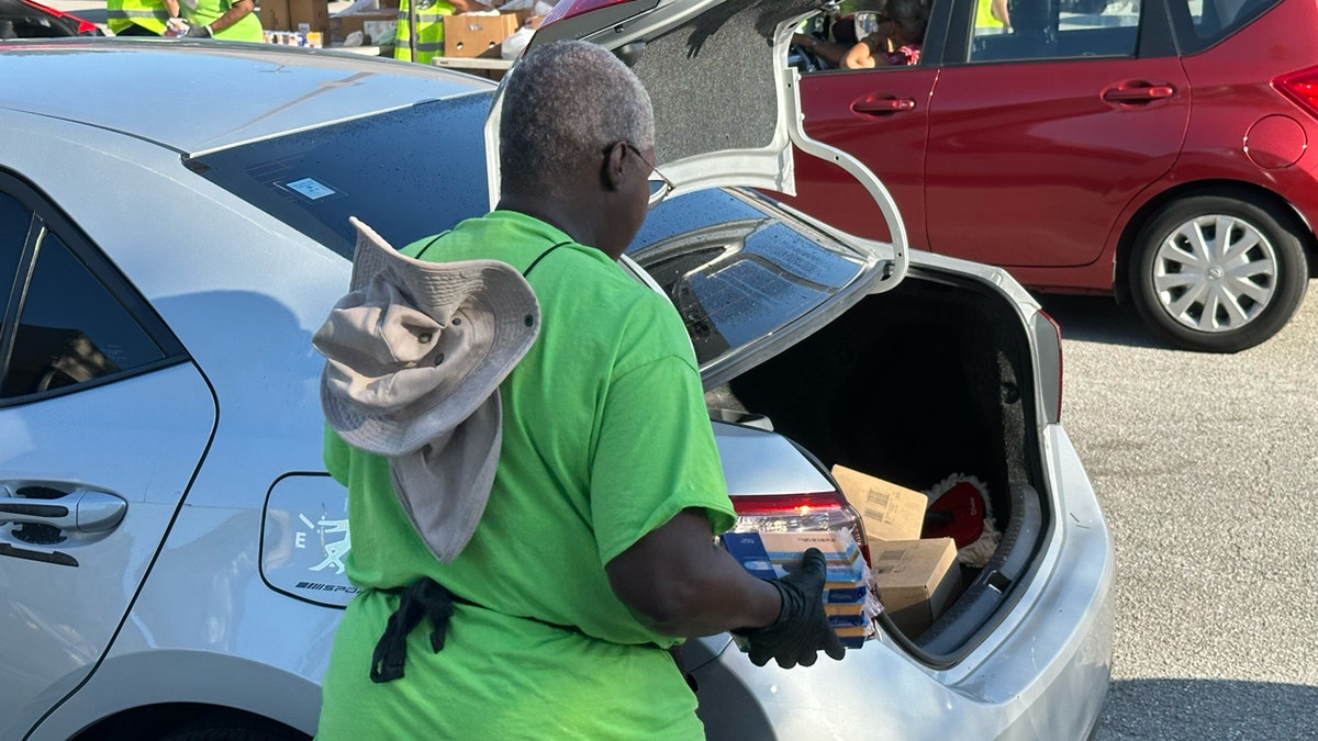 A volunteer loads some cheese into the trunk of a car in line at Place of Hope's drive-thru food distribution.