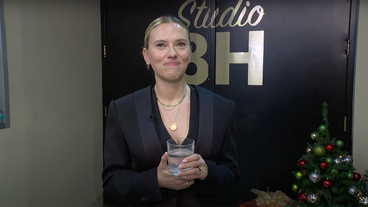 Scarlett Johansson clutches her drink as she stares at the camera backstage at 