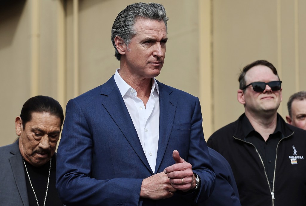 California Governor Gavin Newsom standing with actor Danny Trejo and SAG-AFTRA Executive Director Duncan Crabtree-Ireland at a press conference in Los Angeles