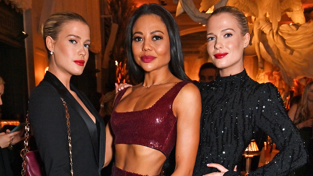 The Spencer sisters wearing black standing in between Emma Thynn wearing a sparkling burgundy top.