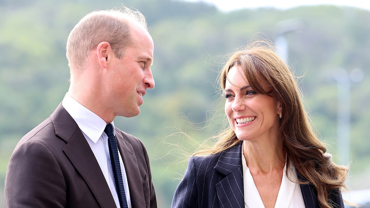 Prince William looking at his wife Kate Middleton who is smiling.