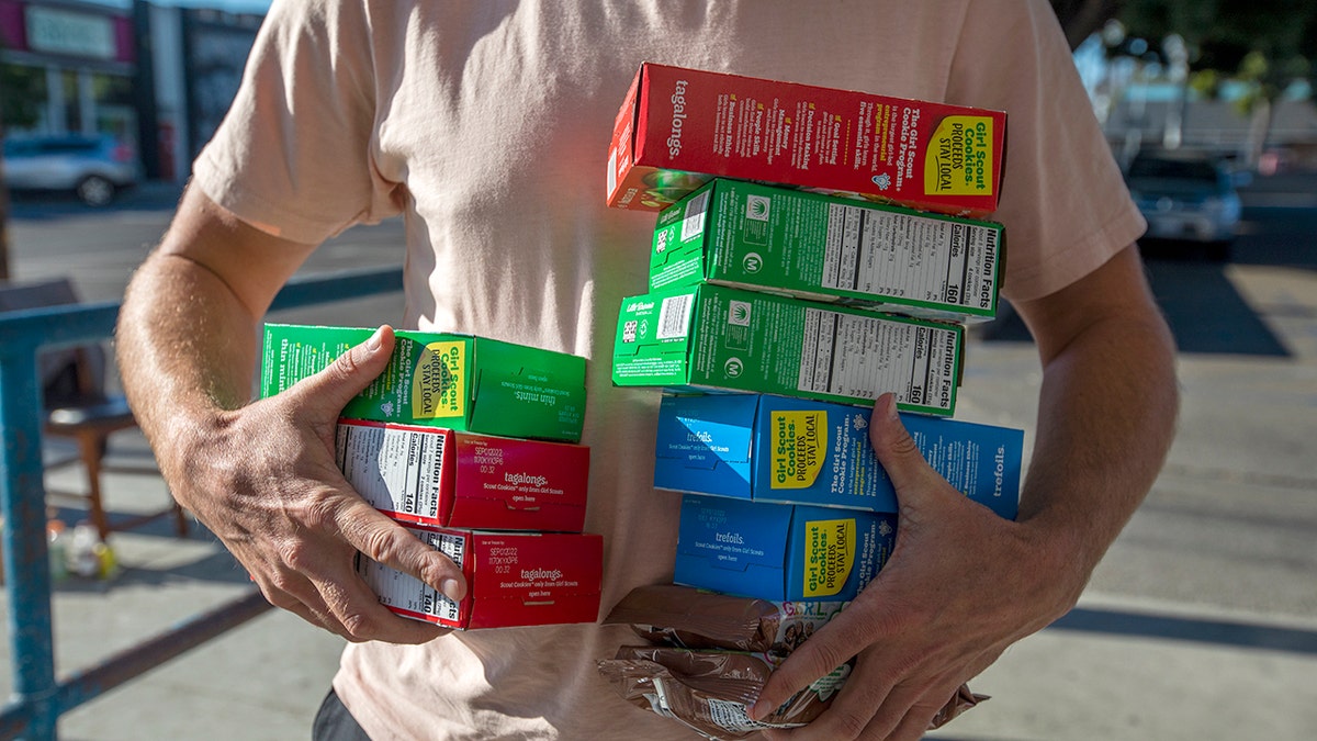 Man holding boxes of girl scout cookies.