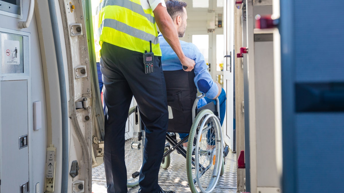 Service man helping disabled passenger to enter on board at airport