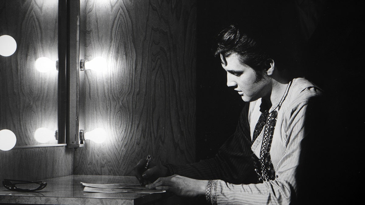 Elvis Presley looking down with lights facing him.