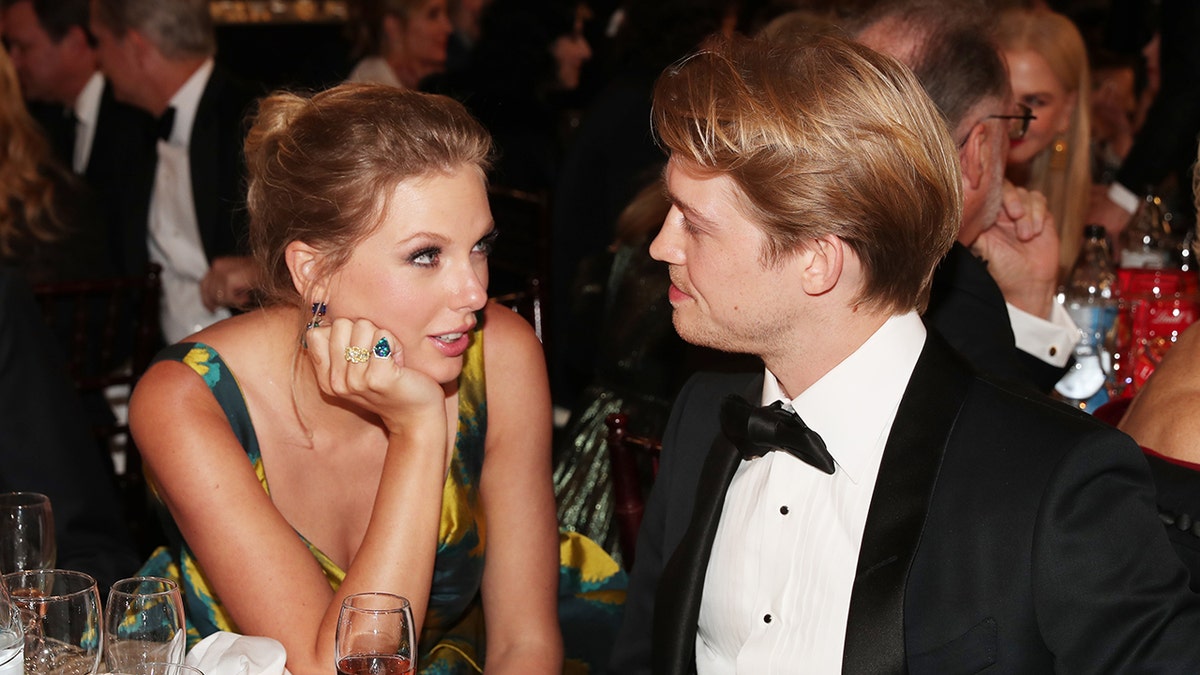 Taylor Swift looks at Joe Alwyn with her hand rested against her face at the Golden Globes